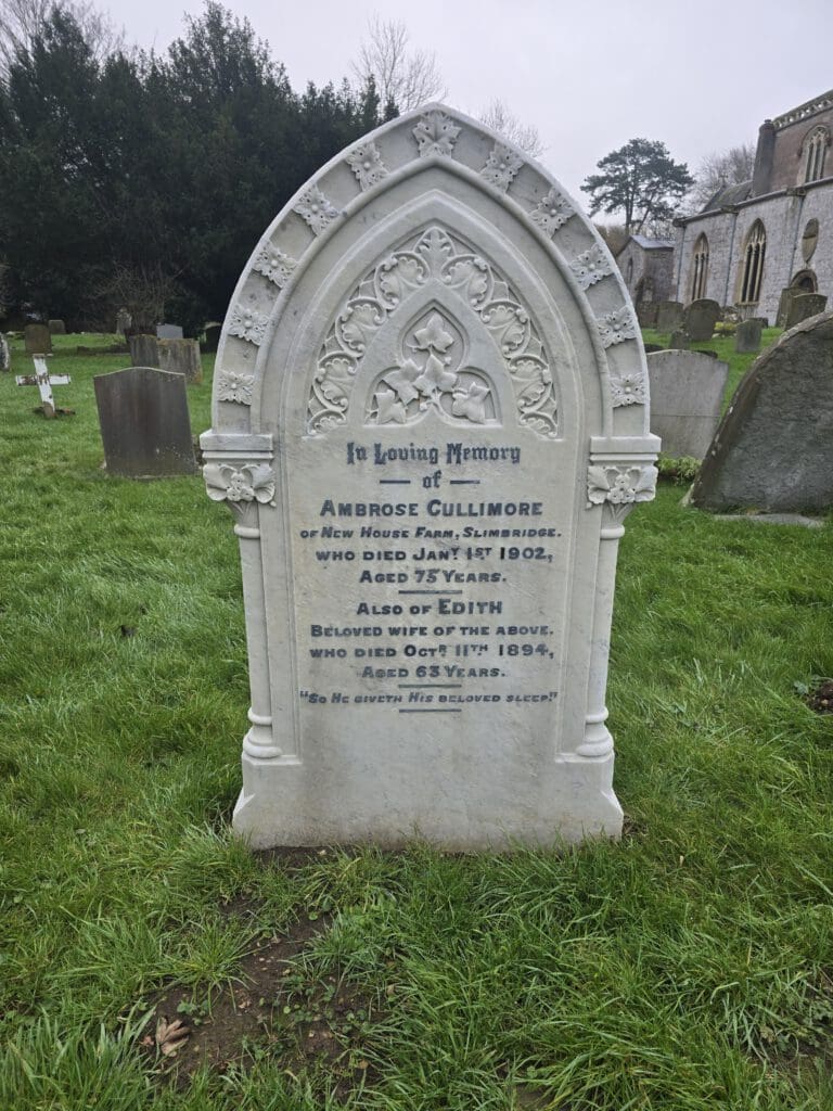 An ornate gravestone surrounded by grass and other headstones in a cemetery. It commemorates Ambrose Cullimore, who died in 1902, and Edith, who died in 1894. A church is visible in the background.
