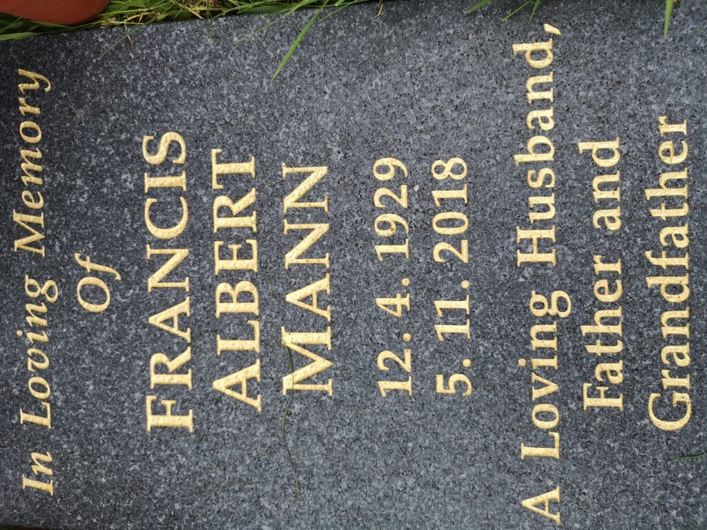 A gravestone with the inscription "In Loving Memory of Francis Albert Mann" and dates "12.4.1929" and "5.11.2018". It also reads "A Loving Husband, Father and Grandfather". The stone is set in grass.