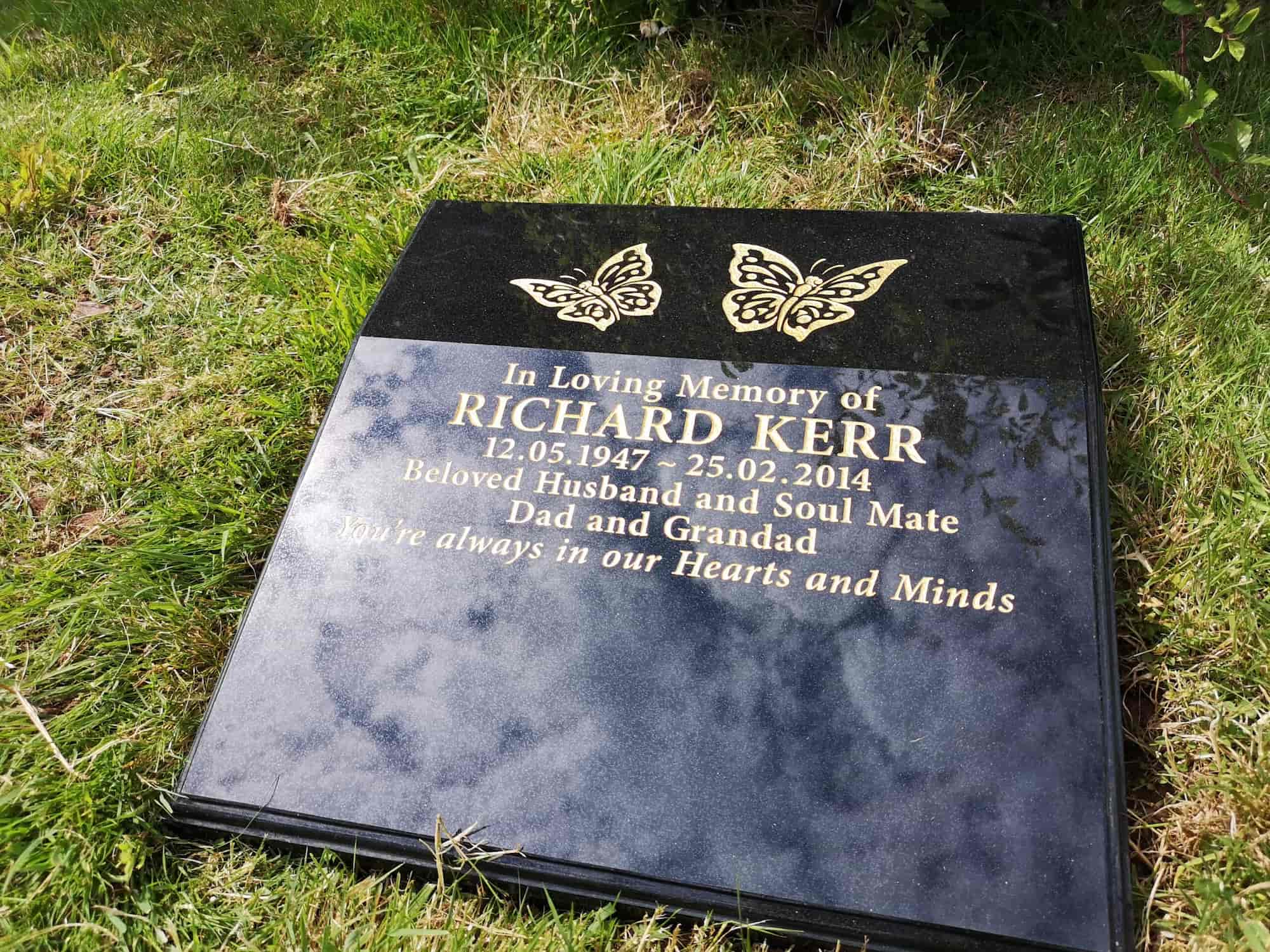 Black gravestone on grass with gold butterfly engravings, commemorating Richard Kerr (1947–2014), beloved husband, soulmate, dad, and grandad. Inscription reads: "You're always in our Hearts and Minds.